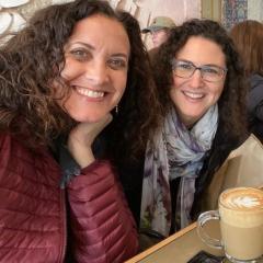 Smiling female cantors with long, dark curly chair looking at the camera in a coffee shop in Jeruslam