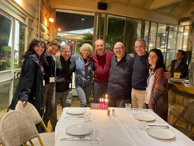 People standing around dinner table smiling at camera ready for their mission to Israel