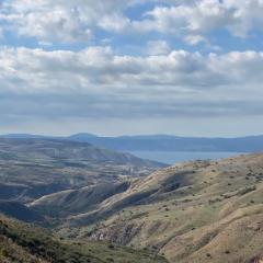 Sea of Galilee seen between brown and green mountains and a blue sky